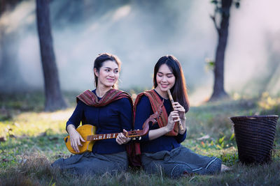 Female friends playing music while sitting on land