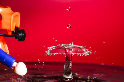 Close-up of toy diver by water against red background