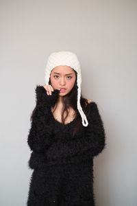 Portrait of young woman wearing mask against white background