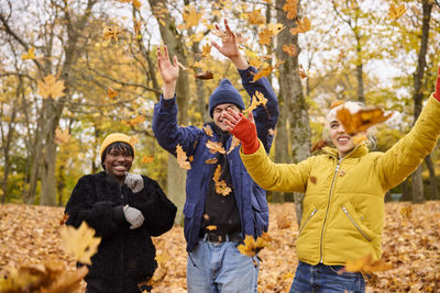 Happy young friends throwing autumn leaves