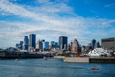 City at waterfront against cloudy sky