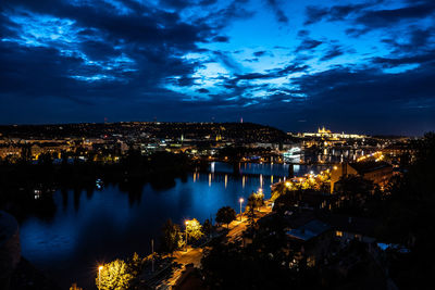 High angle view of illuminated city by river against sky