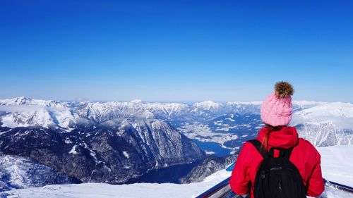 Rear view of person on snowcapped mountains against clear blue sky