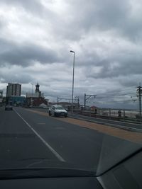 Cars on road against cloudy sky seen through car windshield