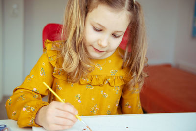 Cute girl painting while sitting at home