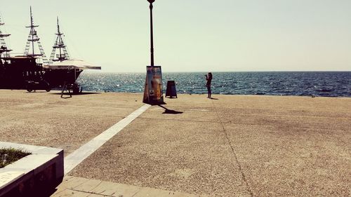 Woman standing at promenade by sea against sky