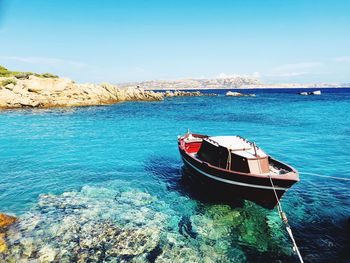 Boat moored on sea shore against sky