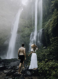 Rear view of people looking at waterfall