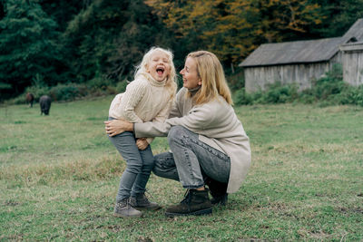 Loving mother tickles her laughing adorable curly little daughter.