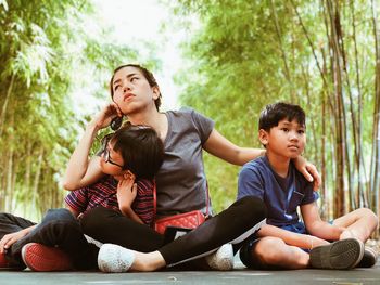 Happy friends sitting against trees