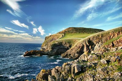 Scenic view of rocky, fenced, green coastline and sea in cornwall, uk