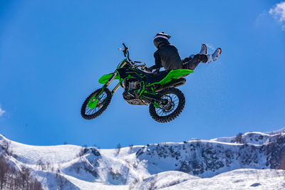 Man riding bicycle on snowcapped mountain against sky