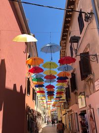 Low angle view of multi colored umbrellas amidst buildings in city against sky