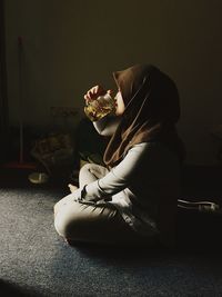 Side view of woman drinking tea at home