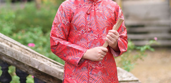 Little boy in traditional vietnamese costume holding a wooden fan