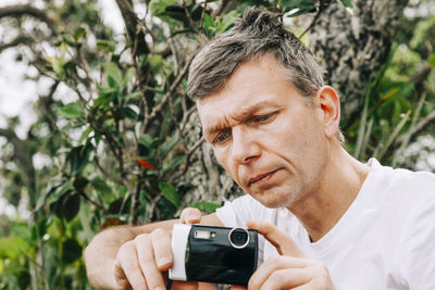 Close-up of man photographing against tree