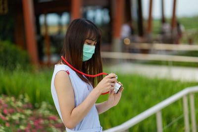 Midsection of woman holding smart phone while standing outdoors