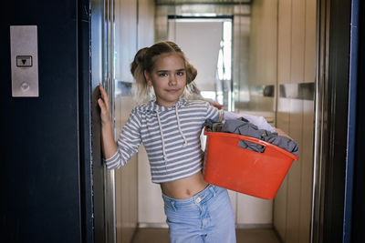 Portrait of young woman standing by window