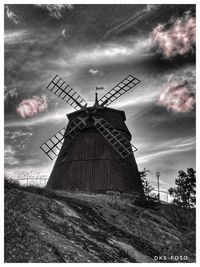 Traditional windmill on landscape against sky