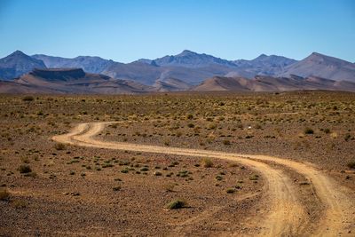 Scenic view of desert against clear blue sky
