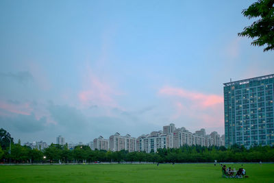 People in park by buildings against sky