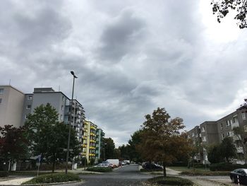 Road by buildings in city against sky