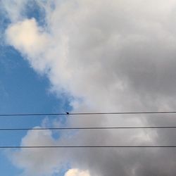 Low angle view of power lines against cloudy sky