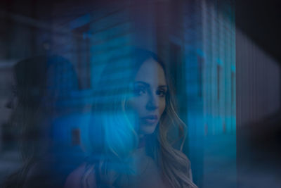 Portrait of young woman looking through window