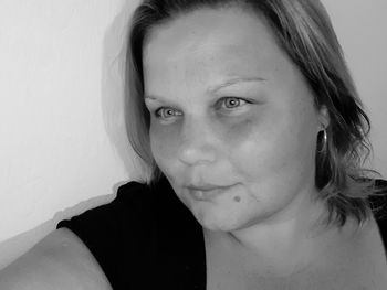 Close-up portrait of woman against wall at home