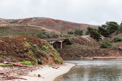 Arch bridge over river amidst mountains against sky