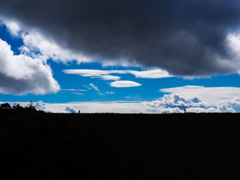 Silhouette landscape against cloudy sky