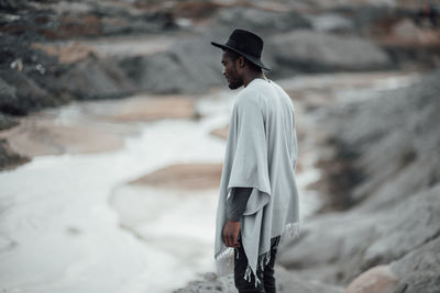 Side view of man wearing hat standing on land