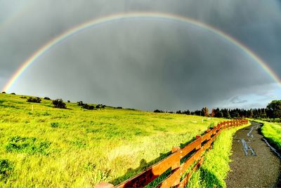 Scenic view of field against rainbow in sky