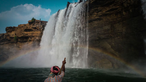 Rear view of man looking at waterfall