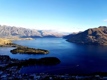 Scenic view of lake and mountains against clear blue sky