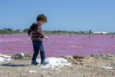 Curly haired boy admiring the pink salt lake la salinas de la mata de torrevieja, alicante region, 