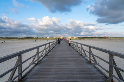 Boardwalk on footbridge against sky