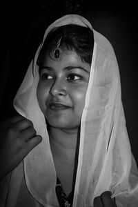 Close-up of young woman in traditional clothes against black background