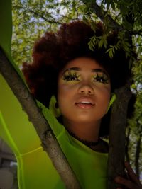 Portrait of smiling young woman against tree trunk