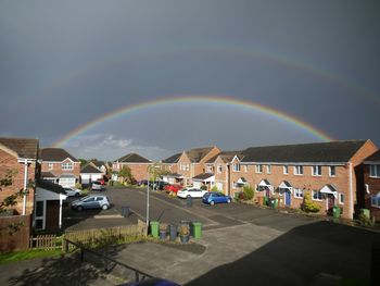 Rainbow over city against sky