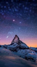 Scenic view of snowcapped mountain against sky at night