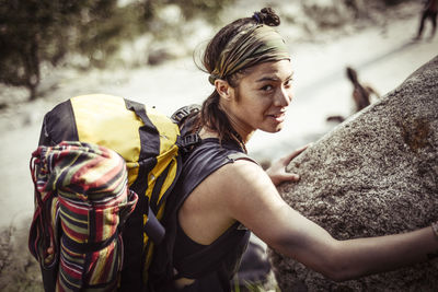 Portrait of smiling woman standing by rock