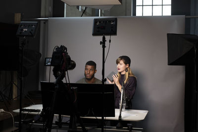 Female entrepreneur explaining about product with male colleague while recording on camera