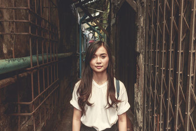 Portrait of young woman standing in alley