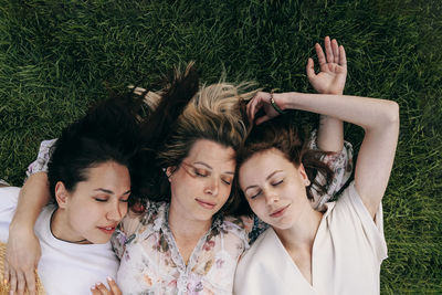 Friends with eyes closed lying on grass at park