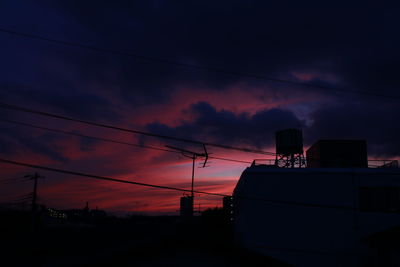 Low angle view of silhouette electricity pylon against sky at sunset