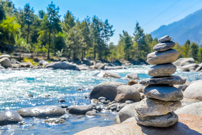 Stack of stones on shore against sky