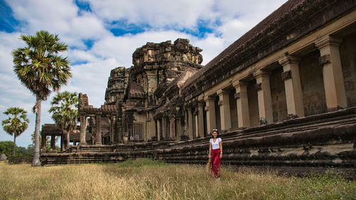 Woman standing by historical building against sky