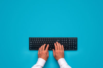 Low section of person using smart phone against blue background