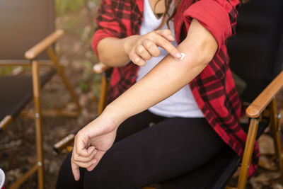 Hand applying topical antihistamine medicine cream on body with severe skin rash and allergy.